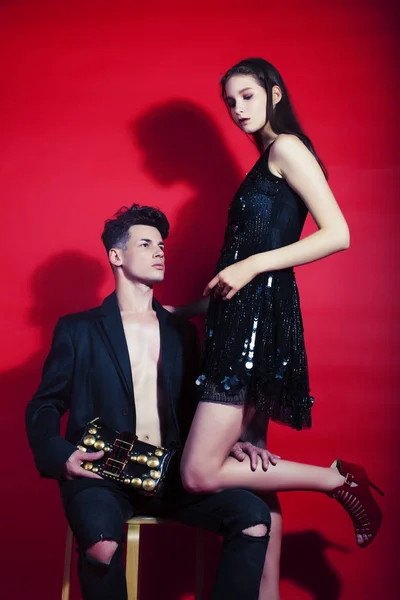young fashion style couple man and woman on red sexy background,