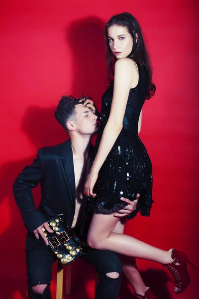 young fashion style couple man and woman on red sexy background,