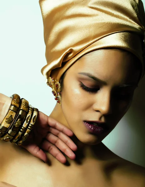beauty african woman in shawl on head, very elegant look with gold jewelry close up mulatto makeup
