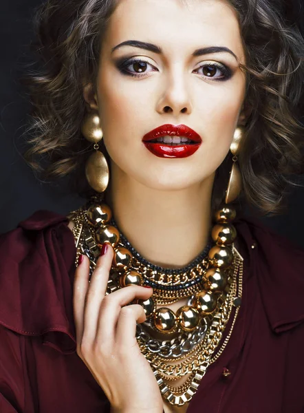 beauty rich brunette woman with a lot of gold jewellery, hispanic curly lady glamour on black background