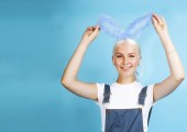 young pretty blond girl with rabbit ears posing cheerful on blue background, lifestyle people concept