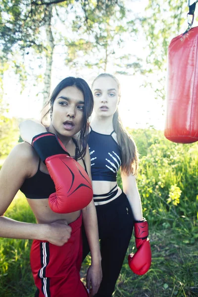 two diverse nations girls fighting boxing outside in green park, sport summer people concept