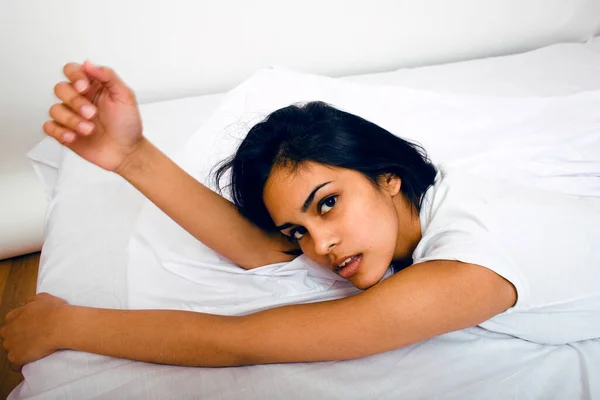 pretty indian brunette real woman in bed smiling, white sheets, tann skin close up mulatto. cant sleep