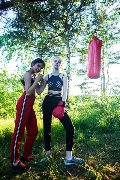 two diverse nations girls fighting boxing outside in green park, sport summer people concept