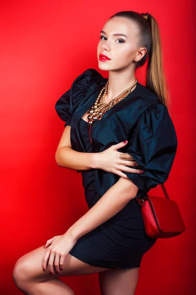 young pretty woman young lady posing on red background wearing gold jewelry, lifestyle people concept