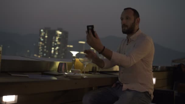 Hombre Joven Con Bebida Tomando Selfie Con Celular En La Terraza En Bar Por La Noche