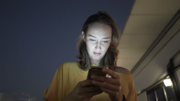 Mujer Joven Mensajes Texto Teléfono Inteligente Sentado Terraza Por Noche — Vídeos de Stock