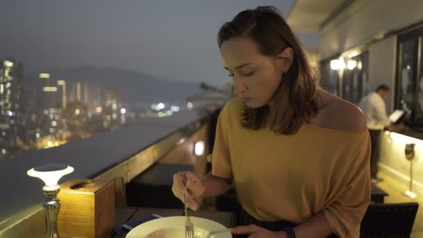テラスに座ってご飯を食べる若い女性は夜のバー — ストック動画
