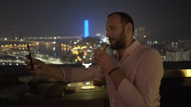 Jovem Com Bebida Tirando Selfie Com Celular Terraço Bar Noite — Vídeo de Stock