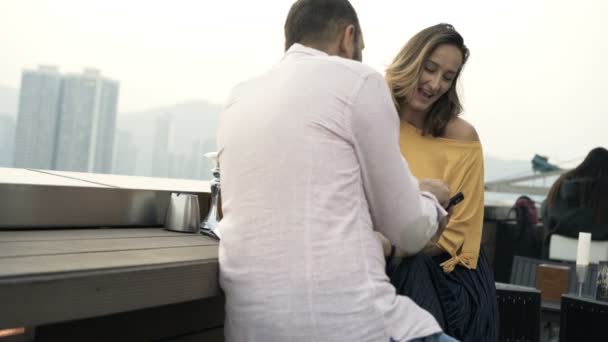 Jovem Casal Com Smartphone Conversando Sentado Terraço Bar — Vídeo de Stock