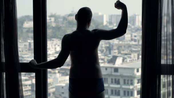 Чоловік Розтягує Руки Шию Захоплюється Видом Вікна Вдома — стокове відео
