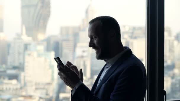 Homme Affaires Prospère Avec Smartphone Debout Près Fenêtre Dans Bureau — Video
