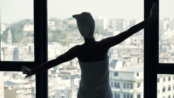 妇女在毛巾伸展胳膊和欣赏看法从窗口在家 — 图库视频影像