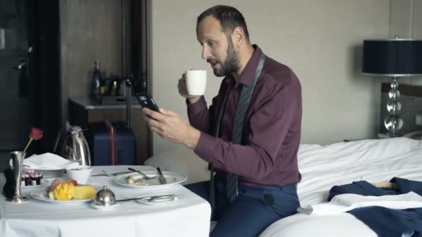 在酒店早餐的年轻生意人聊天在智能手机 — 图库视频影像