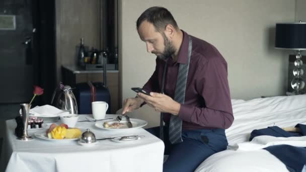 Empresario Mensajes Texto Teléfono Inteligente Durante Desayuno Habitación Del Hotel — Vídeos de Stock