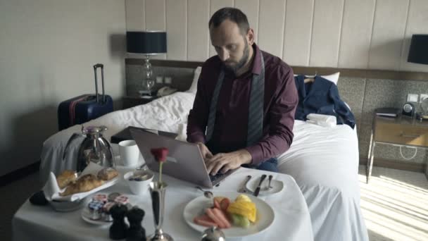 ホテルでの朝食時にラップトップで働く青年実業家 — ストック動画