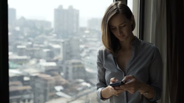 Elegante Mujer Mensajes Texto Teléfono Inteligente Pie Junto Ventana Casa — Vídeo de stock