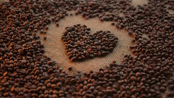 Heart symbol folded from coffee beans. Camera spin. Concept for coffee love or addiction — Stock Video