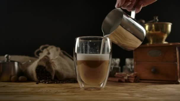 Aufgeschäumte Milch aus einem Barista-Krug in einen Glasbecher mit Kaffee gießen. Latte und Cappuccino zubereiten — Stockvideo