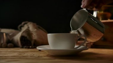 Kahve fincanına köpüklü süt dökmek. Metal modern atıcıdan Latte sanat. 