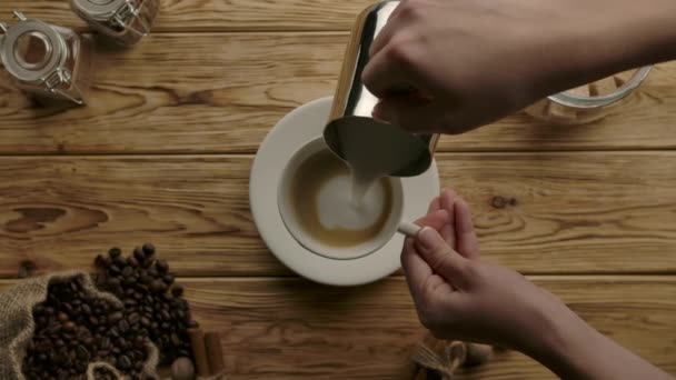 Die Zubereitung des traditionellen Cappuccino. Aufgeschäumte Milch aus Krug in Tasse mit schwarzem Kaffee gießen — Stockvideo