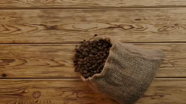 Dispersión de granos de café tostados de la caída de la bolsa de arpillera tradicional. Vista superior, cámara lenta — Vídeos de Stock