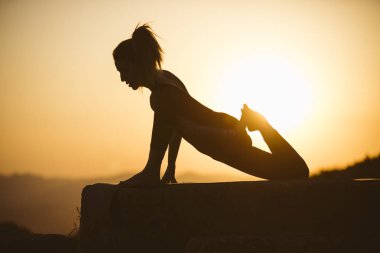 Genç kadın batımında yoga dağda pratiği yapıyor. Pratik yoga açık genç kadın silüeti.