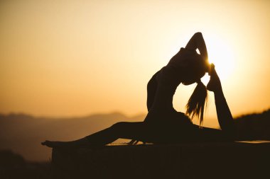 Genç kadın batımında yoga dağda pratiği yapıyor. Pratik yoga açık genç kadın silüeti.