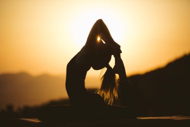 Genç kadın batımında yoga dağda pratiği yapıyor. Pratik yoga açık genç kadın silüeti.