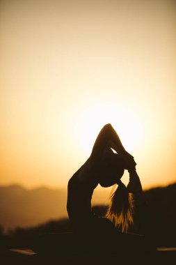 Genç kadın batımında yoga dağda pratiği yapıyor. Pratik yoga açık genç kadın silüeti.