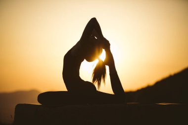 Genç kadın batımında yoga dağda pratiği yapıyor. Pratik yoga açık genç kadın silüeti.