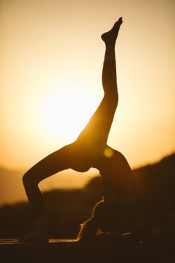 Genç kadın batımında yoga dağda pratiği yapıyor. Pratik yoga açık genç kadın silüeti.