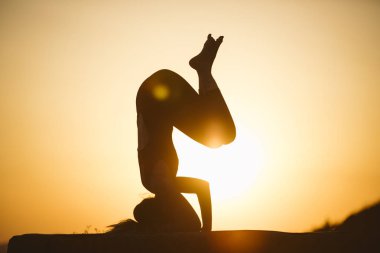 Genç kadın batımında yoga dağda pratiği yapıyor. Pratik yoga açık genç kadın silüeti.