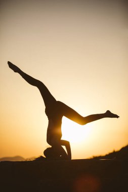 Genç kadın batımında yoga dağda pratiği yapıyor. Pratik yoga açık genç kadın silüeti.
