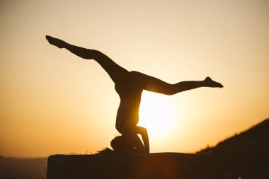 Genç kadın batımında yoga dağda pratiği yapıyor. Pratik yoga açık genç kadın silüeti.