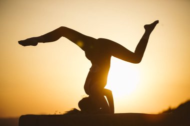 Genç kadın batımında yoga dağda pratiği yapıyor. Pratik yoga açık genç kadın silüeti.