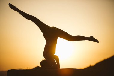 Genç kadın batımında yoga dağda pratiği yapıyor. Pratik yoga açık genç kadın silüeti.