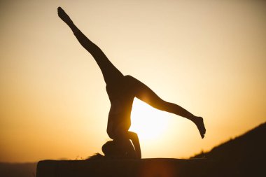 Genç kadın batımında yoga dağda pratiği yapıyor. Pratik yoga açık genç kadın silüeti.