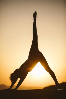 Genç kadın batımında yoga dağda pratiği yapıyor. Pratik yoga açık genç kadın silüeti.