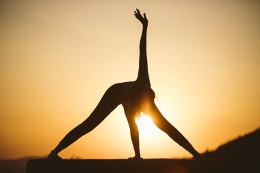 Genç kadın batımında yoga dağda pratiği yapıyor. Pratik yoga açık genç kadın silüeti.