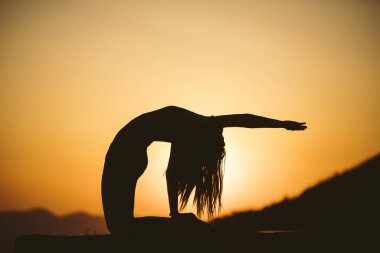 Genç kadın batımında yoga dağda pratiği yapıyor. Pratik yoga açık genç kadın silüeti.
