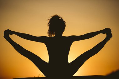 Genç kadın batımında yoga dağda pratiği yapıyor. Pratik yoga açık genç kadın silüeti.