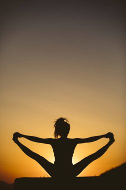 Genç kadın batımında yoga dağda pratiği yapıyor. Pratik yoga açık genç kadın silüeti.