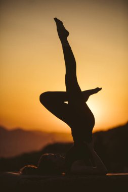 Genç kadın batımında yoga dağda pratiği yapıyor. Pratik yoga açık genç kadın silüeti.