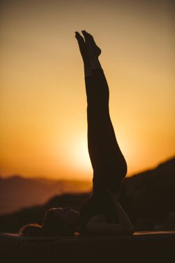 Genç kadın batımında yoga dağda pratiği yapıyor. Pratik yoga açık genç kadın silüeti.