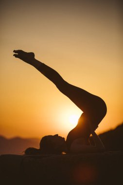 Genç kadın batımında yoga dağda pratiği yapıyor. Pratik yoga açık genç kadın silüeti.