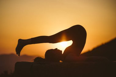 Genç kadın batımında yoga dağda pratiği yapıyor. Pratik yoga açık genç kadın silüeti.