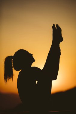 Genç kadın batımında yoga dağda pratiği yapıyor. Pratik yoga açık genç kadın silüeti.