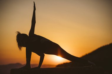 Genç kadın batımında yoga dağda pratiği yapıyor. Pratik yoga açık genç kadın silüeti.