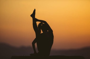 Genç kadın batımında yoga dağda pratiği yapıyor. Pratik yoga açık genç kadın silüeti.